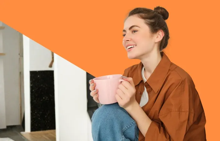 Persona sonriente con una taza sobre fondo naranja de inmho